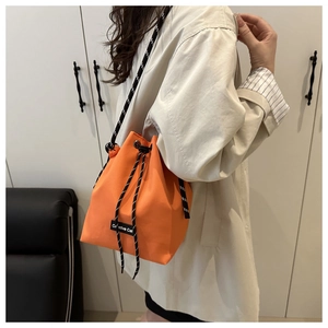 Orange drawstring bucket bag with thick woven straps and Creative Cat label on side