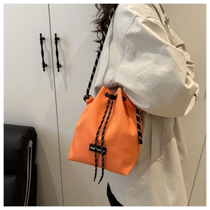 Bright orange drawstring bucket bag with a woven shoulder strap and logo patch