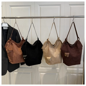 Detailed view of four suede bucket bags in neutral tones hanging on a minimalist rack