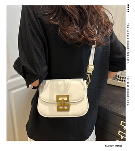 Detailed view of white leather crossbody bag featuring unique interlocking gold buckle