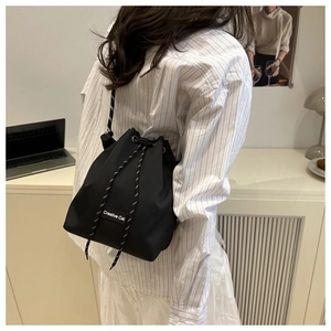 Detail of black drawstring bucket bag with Creative Cat label and woven shoulder strap