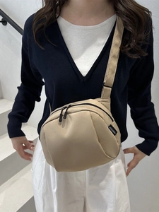 Minimalist beige nylon shell-shaped crossbody bag with adjustable strap and dual zippers