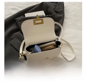 Detail view of white leather crossbody bag interior showing storage space and gold buckle