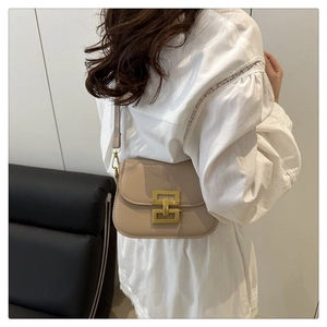 Detail of a beige leather flap shoulder bag with iconic interlocking gold metal buckle