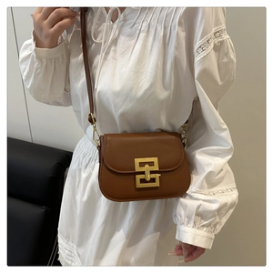 Detail of a brown vintage leather crossbody bag featuring a geometric gold metal buckle