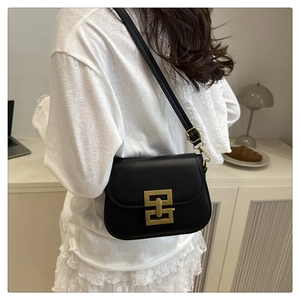 Detail of black crossbody bag with vintage gold interlocking buckle and matte leather texture