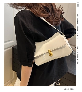Detail of white patent leather underarm bag with elegant gold twist lock clasp
