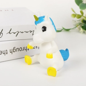 Simpatico giocattolo unicorno bianco con criniera blu e corno giallo su tavolo bianco