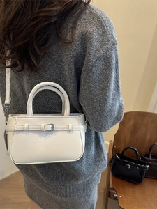 Elegant creamy white crossbody handbag with thin belt buckle accents and a top handle