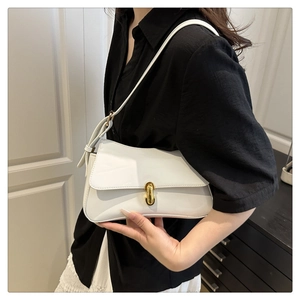 Close-up of white glossy leather underarm bag with gold horseshoe-shaped twist lock