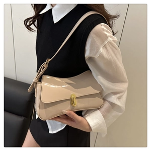 Detail of glossy beige underarm bag featuring a gold oval twist lock and adjustable strap