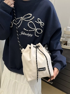 Minimalist white drawstring bucket bag with Creative Cat label and bicolor rope strap