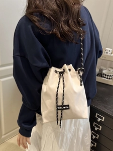 Chic off-white canvas drawstring bucket bag with Creative Cat label and woven shoulder strap