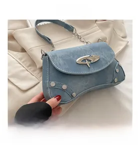 Detail of blue denim shoulder bag featuring silver rivets and star metal buckle