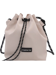 Minimalist beige drawstring bucket bag featuring a Creative Cat patch and woven cord