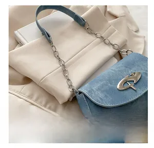 Close-up of blue denim underarm bag with thick silver chain and metal rivet details