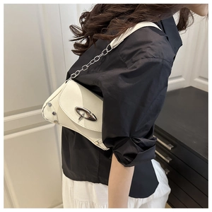 Detail of white lychee leather shoulder bag with silver oval buckle and chain strap