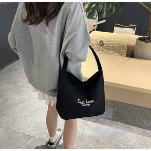Gros plan détaillé du sac hobo en toile noire avec texte blanc C'est lavie porté