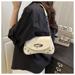 Close-up of beige leather shoulder bag with silver hardware on model's shoulder