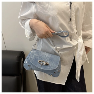 Detail of light blue denim handbag with silver studs and streamlined metallic logo