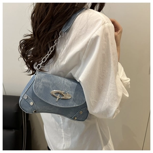 Detail view of light blue denim Y2K shoulder bag with silver buckles and studs on model