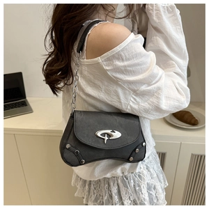 Detail view of a charcoal crossbody bag with silver rivet trim and metal buckle on a model