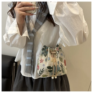 Detail of vintage floral embroidery drawstring bucket bag with pearl charms and chain