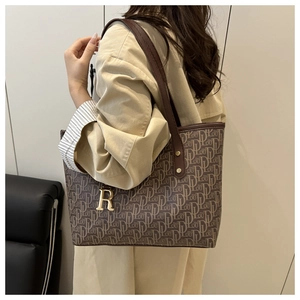 Detail of vintage monogram tote bag with brown leather straps and gold R pendant