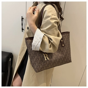 Detail of brown tote bag with letter print and golden R letter pendant accessory