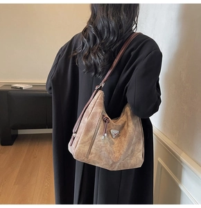 Sac hobo vintage marron avec bandoulière en cuir et logo métallique triangulaire