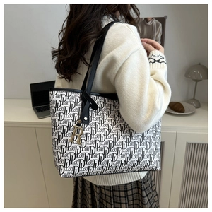 Détail d'un grand sac cabas avec motif monogramme et pendentif en métal doré lettre R