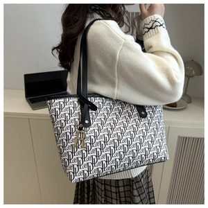 Close-up of a large off-white monogram tote bag with chic black shoulder straps and R-pendant