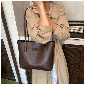 Close-up of a vintage brown leather tote bag featuring a Fashion embossed logo detail