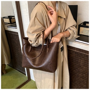 Detail of dark brown leather tote bag with FASHION embossed logo and vintage texture