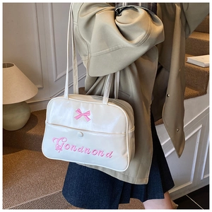Detail der weißen PU-Leder-Einkaufstasche mit rosa Schleifenstickerei und Fronttasche am Modell