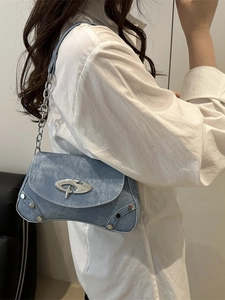 Light blue denim shoulder bag with star logo and silver studs shown on a female model