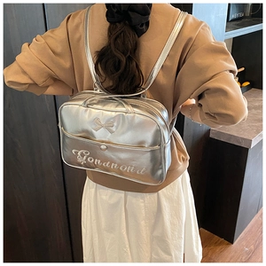 Detail of silver metallic backpack featuring a central bow and fine embroidery texture