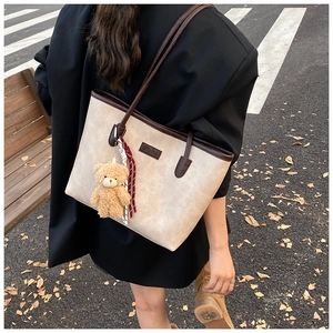 Detail of a large tote bag with bear charm and Fashion label shown on model