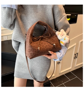 Détail du sac polochon léopard avec nœud et breloque peluche en bandoulière