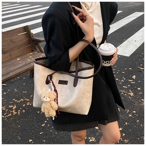 Detail of cream tote bag with dark brown straps and fashion label on street background