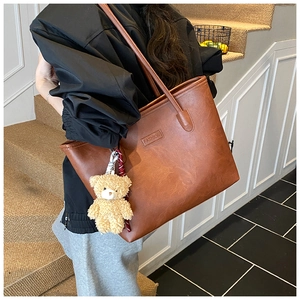 Close-up of large brown tote bag with vintage texture and cute plush bear charm