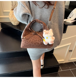 Détail du sac cabas léopard avec un pendentif chat en peluche et une bandoulière réglable
