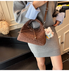 Détail d'un sac à main léopard avec un nœud décoratif et un pendentif animal en peluche