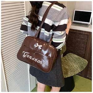 Detail of dark brown faux leather backpack with white bow and cursive text on a model