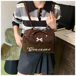 Detail der braunen Lackleder-Tasche mit weißer Schleifen-Stickerei und Logo