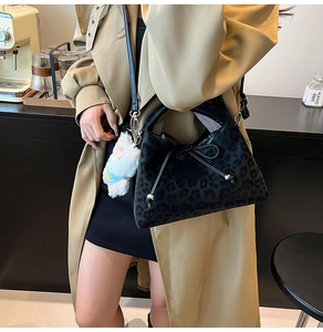 Détail du sac cabas léopard noir avec pendentif en peluche et décoration de nœud en ruban