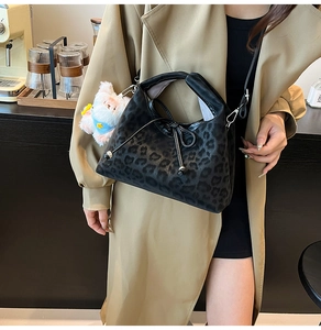 Détail du sac bandoulière léopard noir avec breloque ours en peluche et nœud