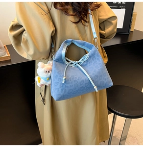 Détail du sac bandoulière bleu clair à motif léopard avec nœud et breloque mouton