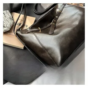 Detail view of vintage dark brown leather bag showing glossy texture and gold metal buckle