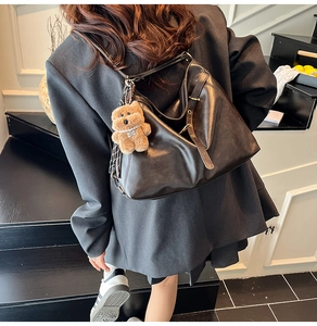 Detail of vintage brown leather tote bag with adjustable metal buckle and plush bear charm